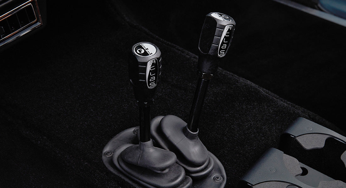 Two black gear levers with 'Atlas' labels on black carpet floor
