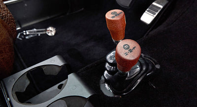 Two gear shift knobs with worn brown wood finish on classic vehicle floor