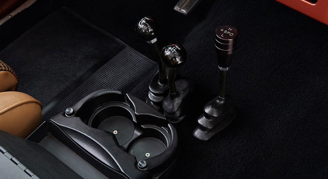 Floor area with three gear shift levers and cup holders inside Classic Ford Bronco