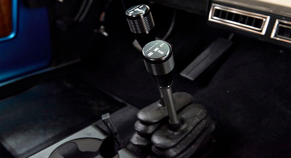 Two transfer case shifters with gear markings inside Classic Ford Bronco