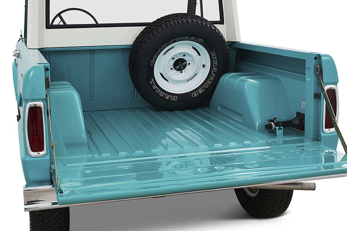 Open turquoise truckbed with mounted spare tire inside Classic Ford Bronco