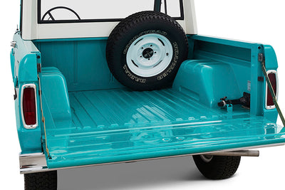 Open turquoise truckbed with mounted spare tire inside Classic Ford Bronco