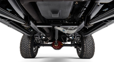 Undercarriage view of Classic Ford Bronco showing suspension, exhaust, and large off-road tires.