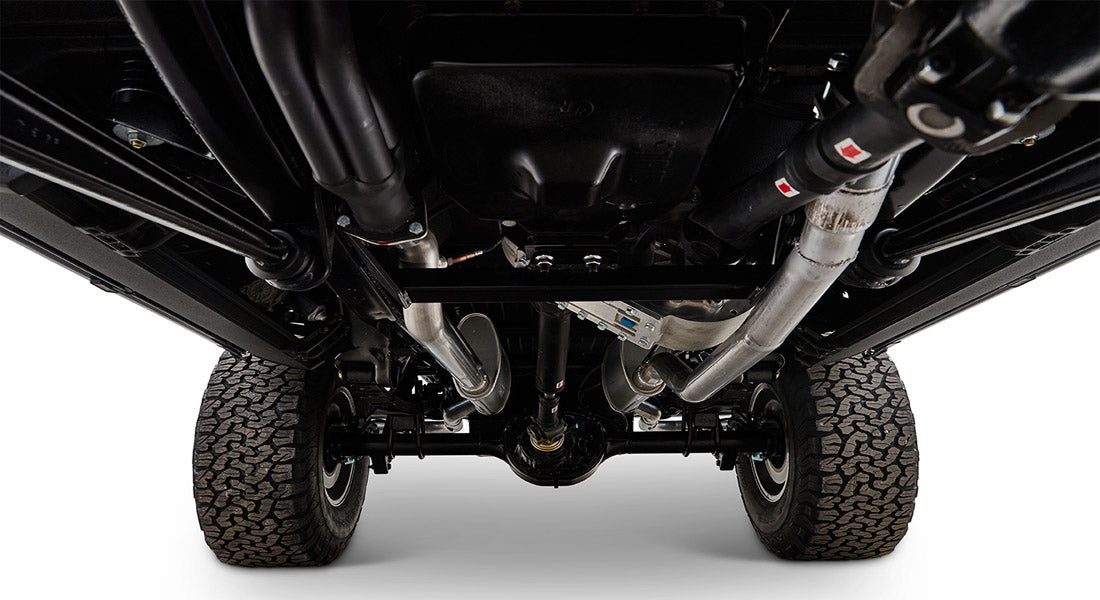 Undercarriage of vehicle showing axles, exhaust, and tires from below