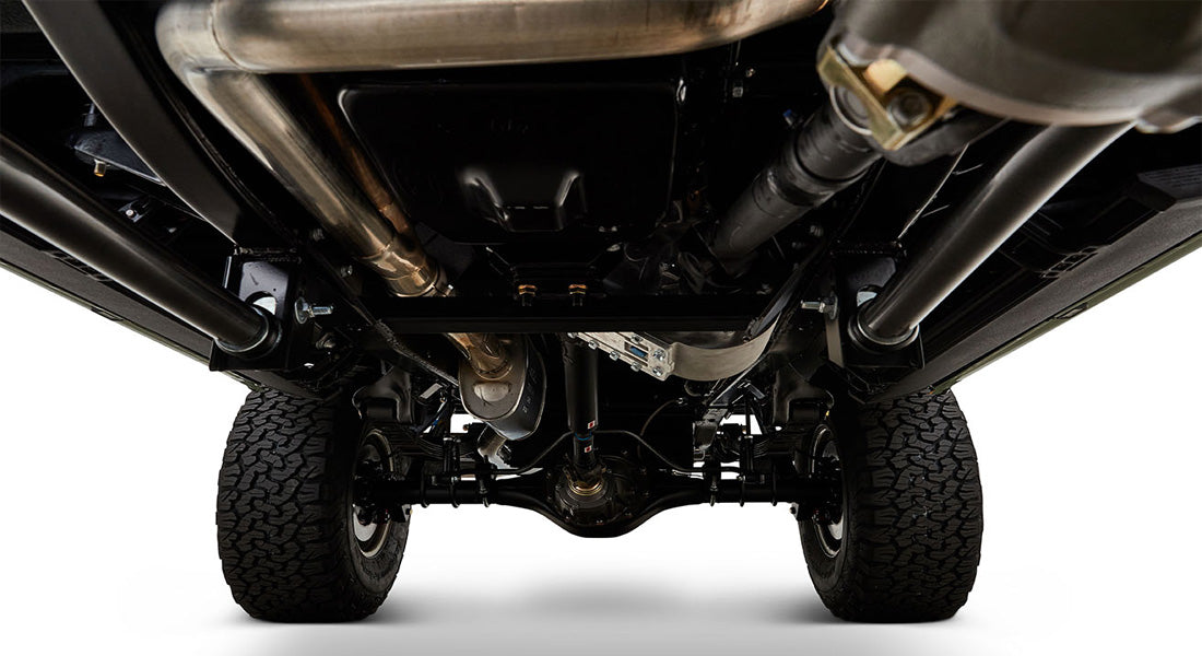 Undercarriage view showing suspension, exhaust system, and tires of a Classic Ford Bronco.