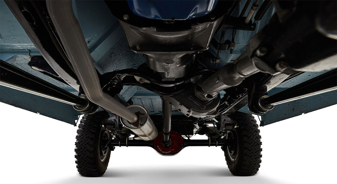 Undercarriage view showing exhaust pipe, drivetrain, and rear axle of a Classic Ford Bronco