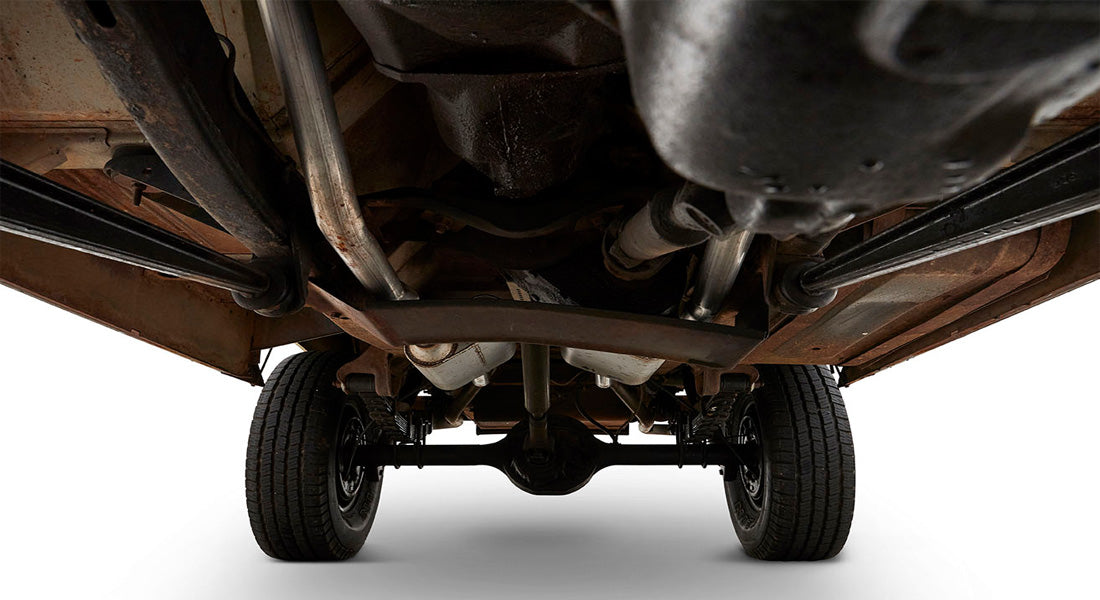 Rusty undercarriage with suspension and exhaust pipes viewed from below a Classic Ford Bronco