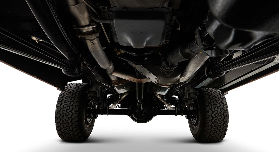 Undercarriage of Classic Ford Bronco showing exhaust system and tires against white background