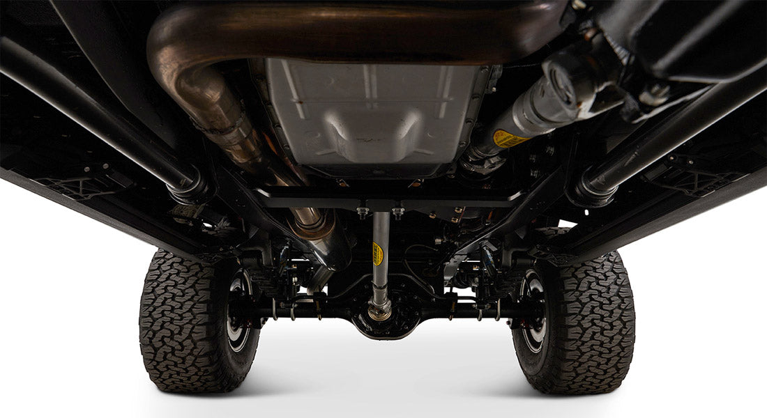 Undercarriage view showing suspension, drive shaft, and tires of a Classic Ford Bronco