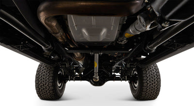 Undercarriage view showing suspension, drive shaft, and tires of a Classic Ford Bronco