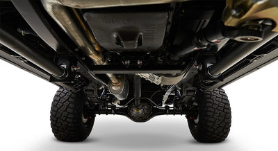 Undercarriage view with differential, suspension components, exhaust pipes, and off-road tires