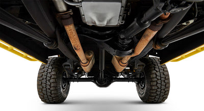 Undercarriage view showing suspension and dual rusted exhaust pipes of a Classic Ford Bronco