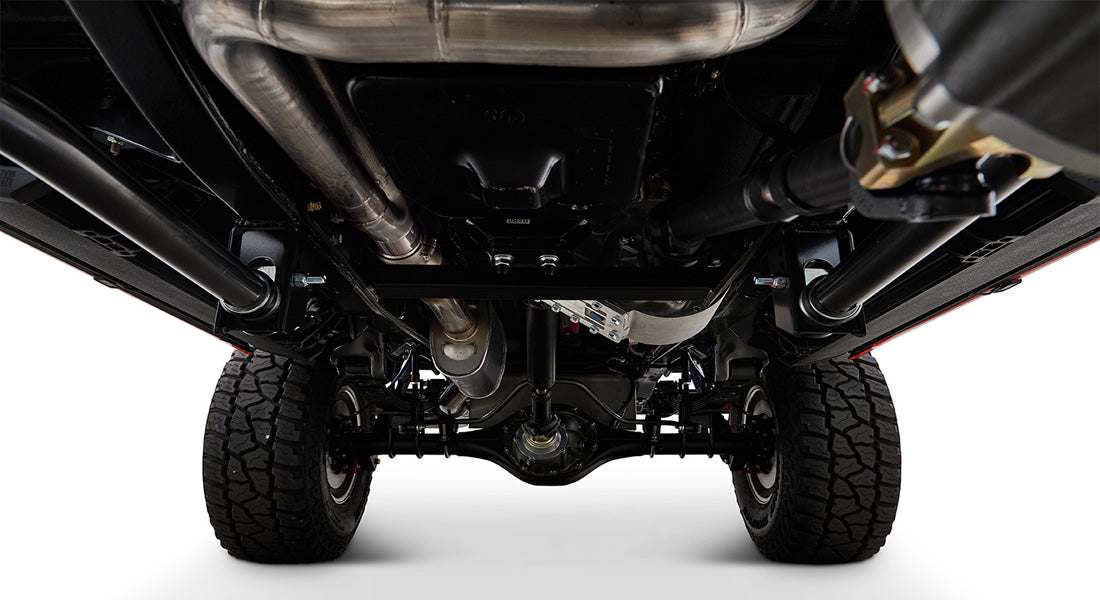 Undercarriage view showing suspension, exhaust pipes, and tires of Classic Ford Bronco