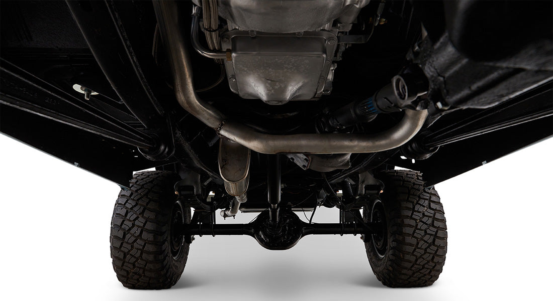 Undercarriage of Classic Ford Bronco displaying exhaust pipes, differential, and tires