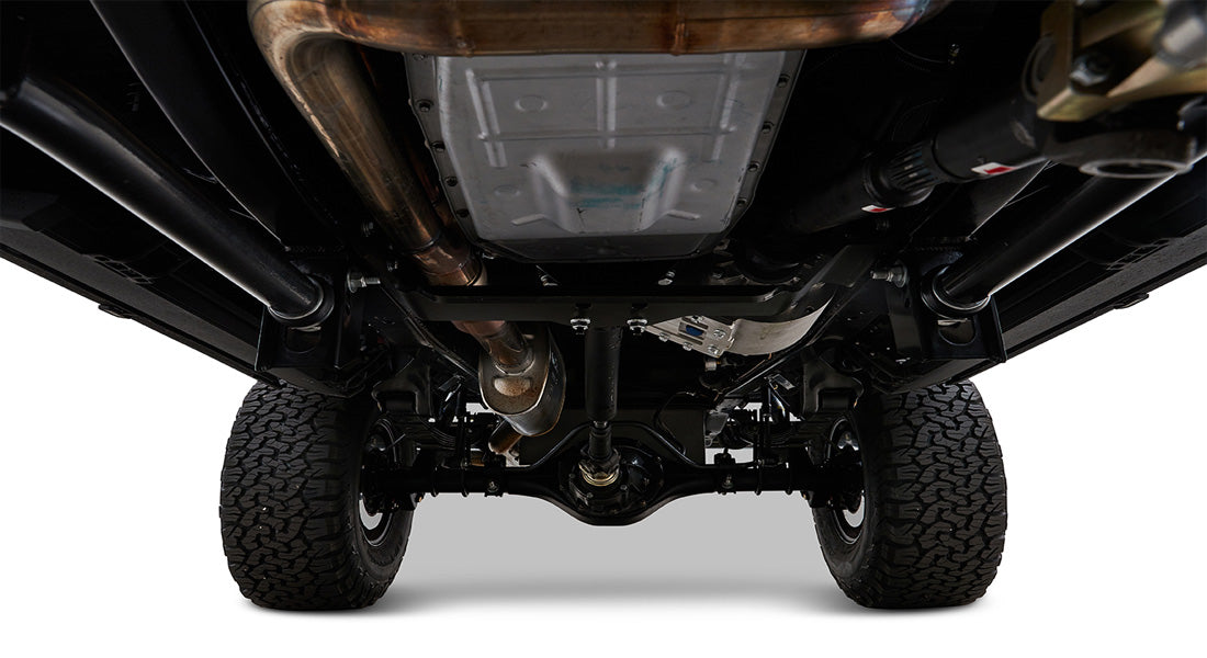 Undercarriage view of vehicle showing drive shaft, exhaust system, differential, and tires