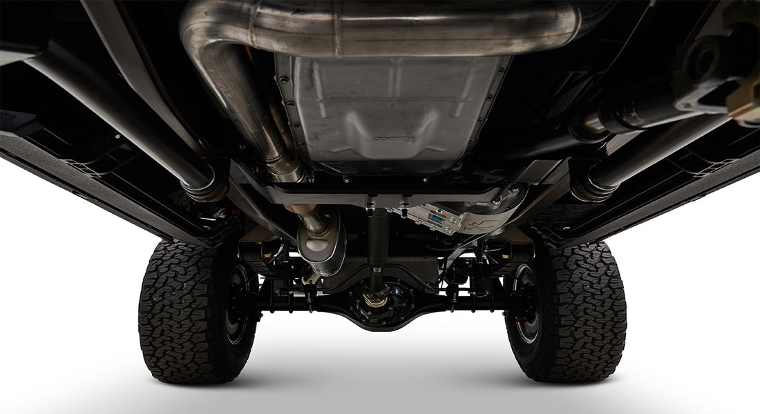 Undercarriage view of a Classic Ford Bronco showing suspension, exhaust, and tires from ground level