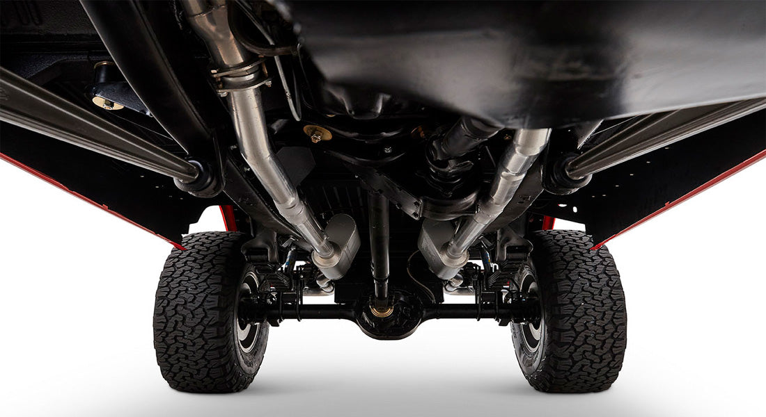 Undercarriage view showing exhaust system, suspension, and tires on black chassis