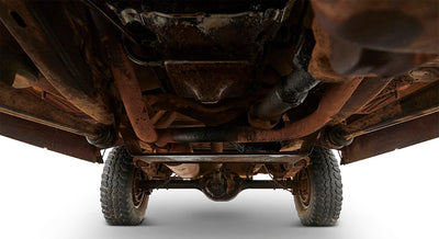 Undercarriage of older Classic Ford Bronco showing frame, suspension, and tires with rusted components