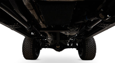 Undercarriage view showing suspension, axle, exhaust, and tires against white background