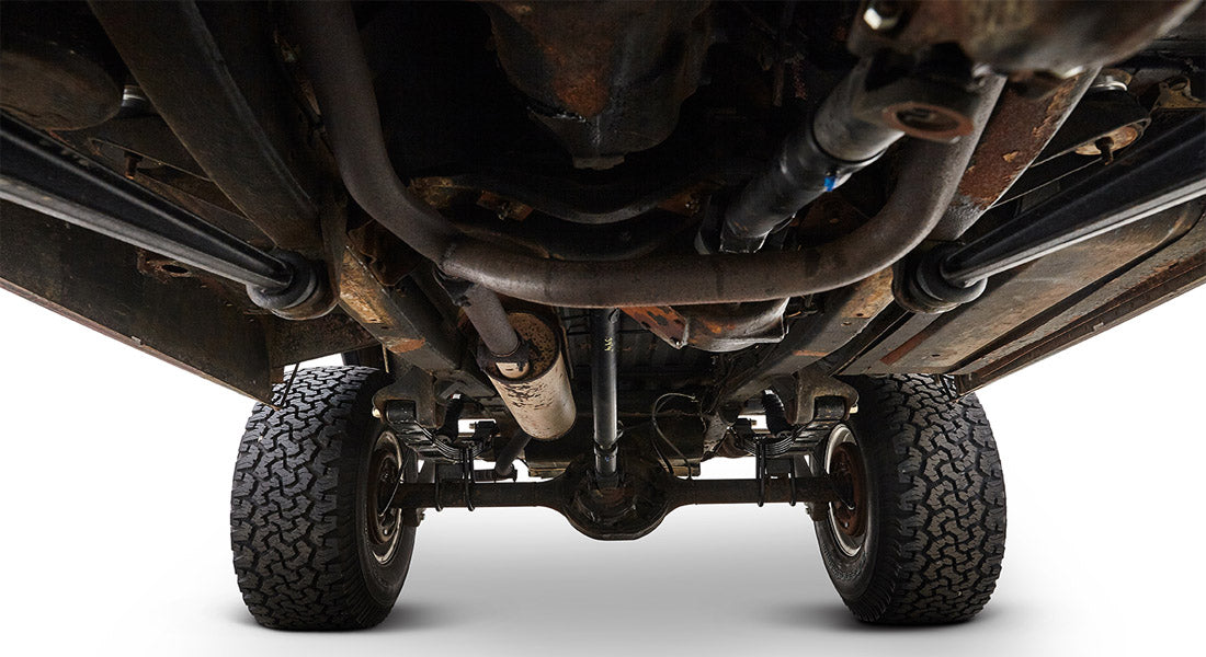 Undercarriage of a Classic Ford Bronco showing suspension, exhaust, and tires from below