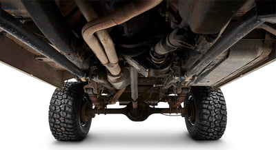 Undercarriage view of Classic Ford Bronco showing exhaust, suspension, and tires against white background.
