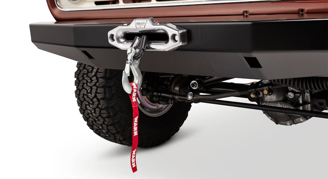 Classic Ford Bronco front bumper with a silver WARN winch and large off-road tire visible behind